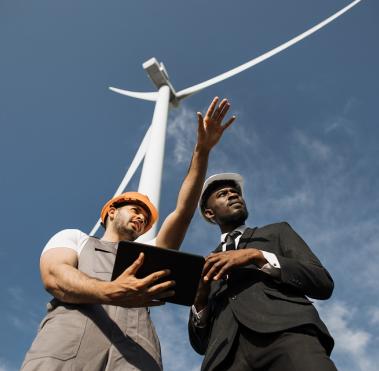 Engineers with helmets standing on farms with windmills